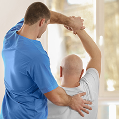 Fyzioterapeut cvičí s pacientom, ktorý trpí osteoporózou.