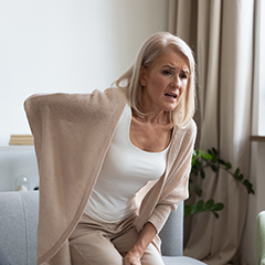 Príznaky osteoporózy: žena trpiaca bolesťou dolnej časti chrbtice.