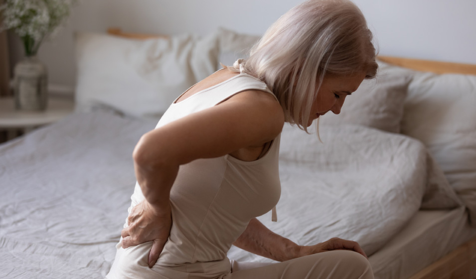 Žena s osteoporózou trpiaca bolesťami dolnej časti chrbta.